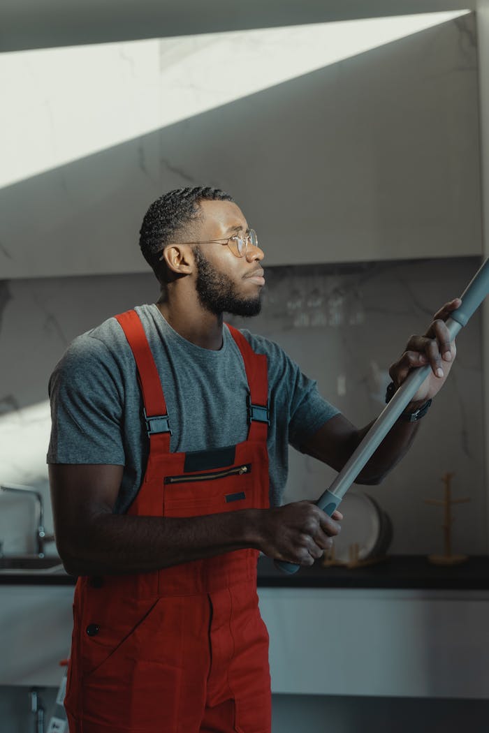 A man in red overalls diligently cleans a kitchen surface, emphasizing focus and cleanliness.